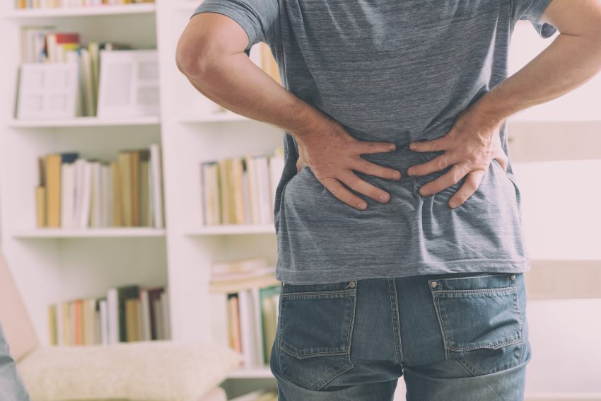 Man in home office suffering from low back pain standin